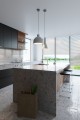 Lampa sufitowa wisząca betonowa szara. Widok w kuchni na wyspę kuchenną. Nad wyspą wiszą lampy betonowe. Styl loft i industrialny.